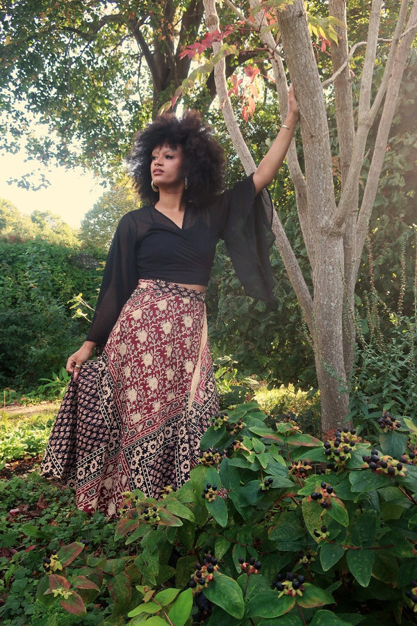 Model wears our Emmylou Patchwork Wrap Skirt in Cherry Red & Black. Worn wrapped around high waisted, showing off the vintage inspired floral block print made from Indian cotton by All About Audrey.