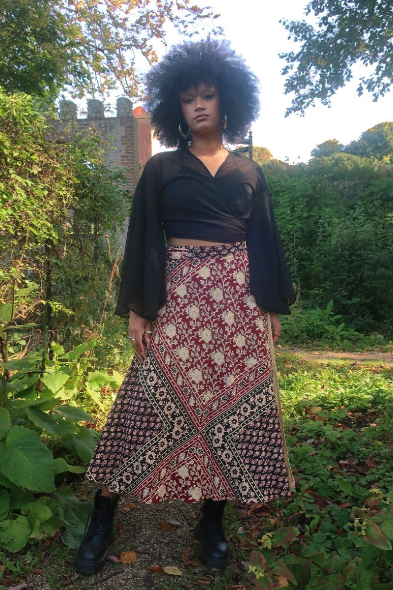 Model wears our Emmylou Patchwork Wrap Skirt in Cherry Red & Black. Worn wrapped around high waisted, showing off the vintage inspired floral block print made from Indian cotton by All About Audrey.