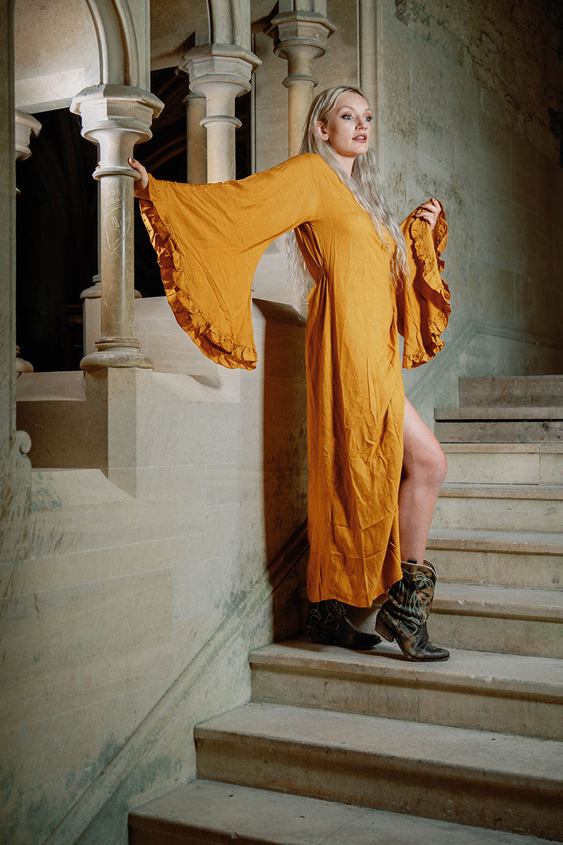 Model wears Venus maxi wrap dress in Mustard Yellow rayon fabric. Beautiful floaty oversized butterfly sleeves and an adjustable waist by All About Audrey