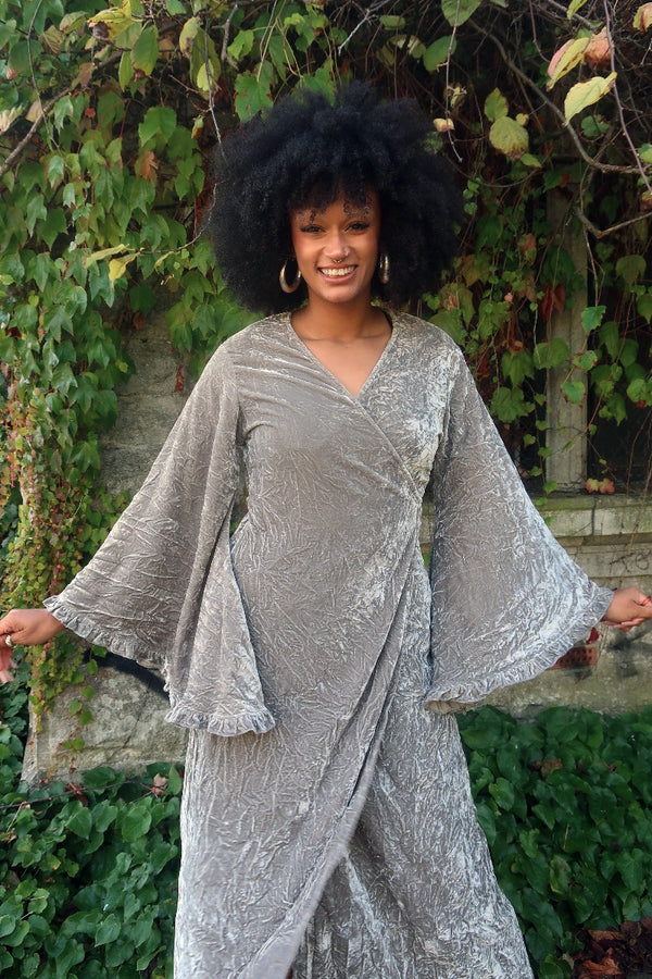 Model wears our Khroma Venus Maxi Dress as a wrap style, tied at the back and showing off the huge retro floaty bell sleeves. A beautiful Stardust Grey Velvet by All About Audrey