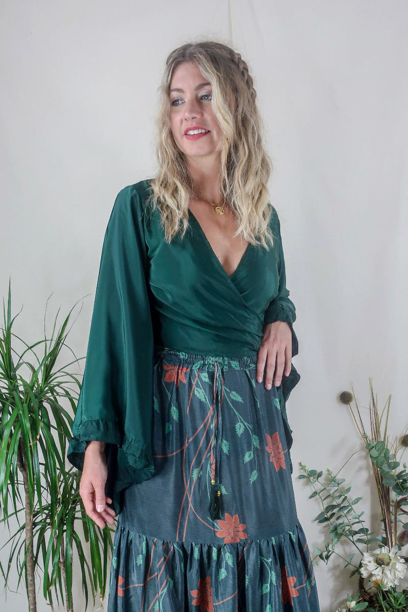Model wears our Venus Khroma wrap top in Archer Green. A gorgeous deep pine green tone with retro floaty frill bell sleeves by All About Audrey
