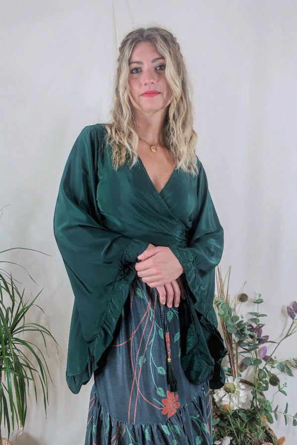 Model wears our Venus Khroma wrap top in Archer Green. A gorgeous deep pine green tone with retro floaty frill bell sleeves by All About Audrey