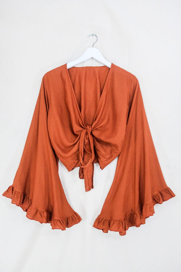 Flatlay photo of our Khroma Venus Wrap Top in Red Clay by All About Audrey