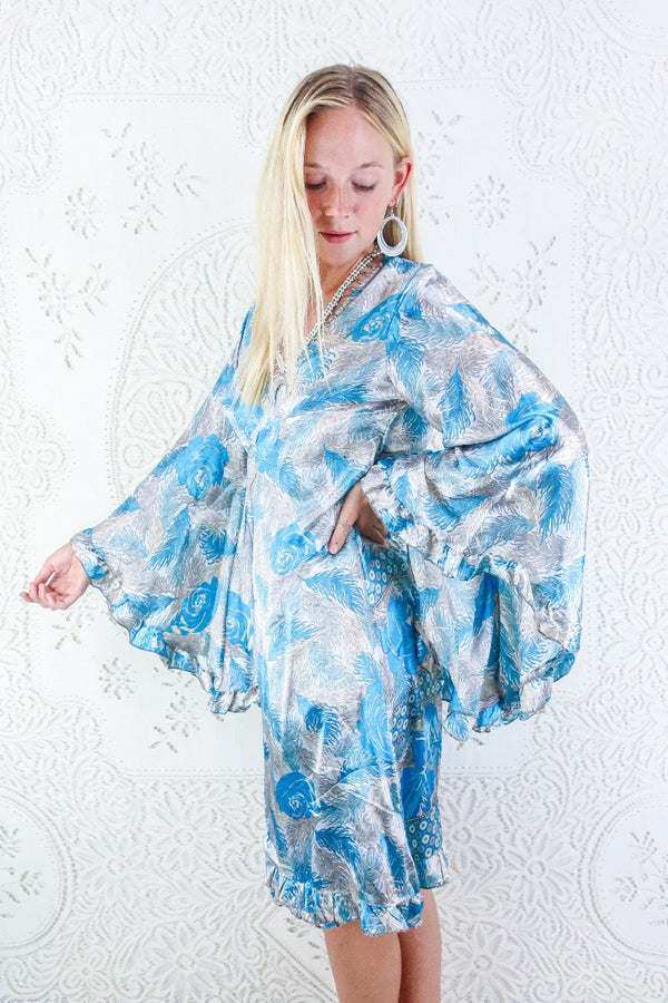 Our model wearing our Venus midi wrap dress in Silver & Azure Blue Fern Floral. Size L/XL By All About Audrey