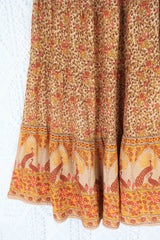detail showing contrast hemline on model wears peacock prairie maxi skirt in tan and turmeric indian style printed sustainable rayon all about audrey