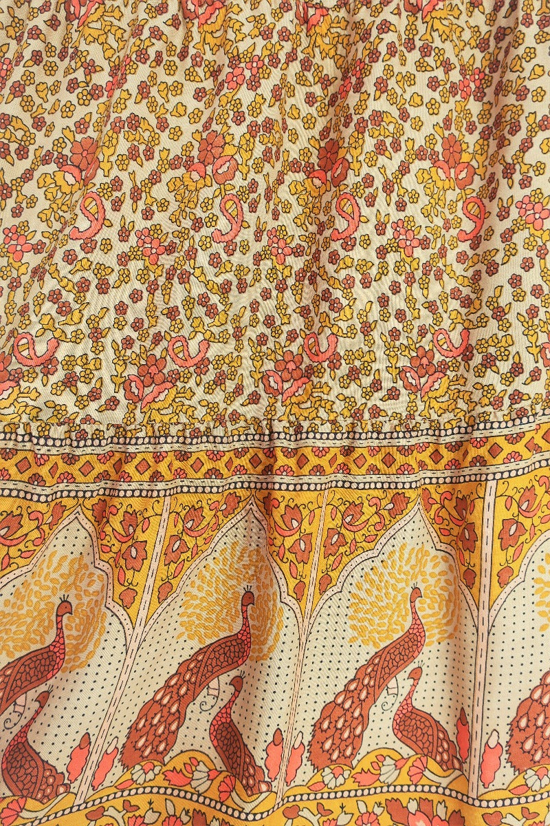 close up to show contrasting peacock block style print on hem of model wears peacock prairie maxi skirt in tan and turmeric indian style printed sustainable rayon all about audrey