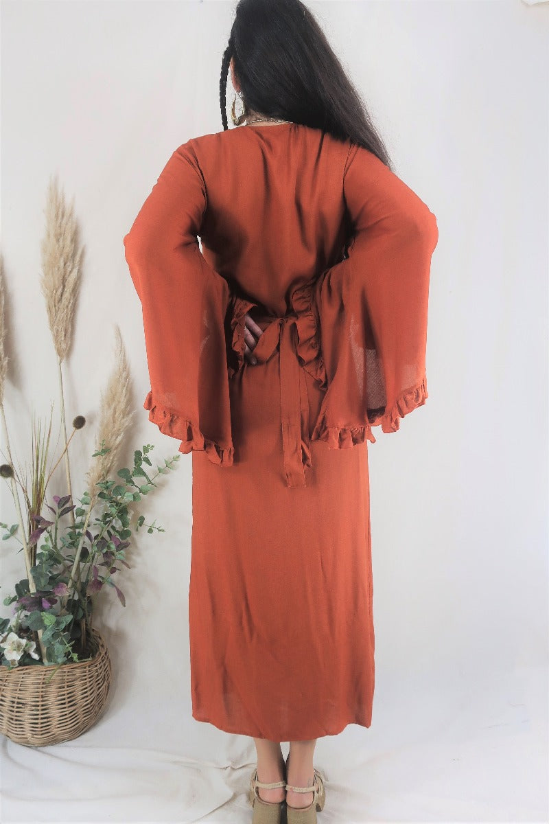 Back photo of the Venus maxi bell sleeve dress. Showing the adjustable tie waist, oversized ruffle bell sleeves and vibrant organic red clay colour By All About Audrey