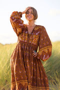Audrey wears our Peacock Primrose Dress in Gingerbread. A dark brown tone with an earth tone peacock and floral print. Inspired by 1970s bohemia by All About Audrey