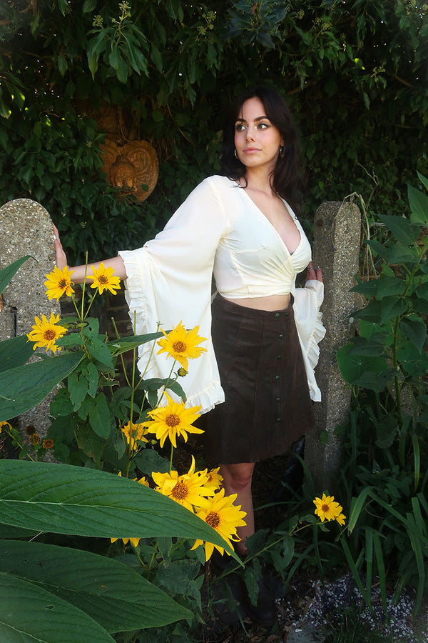 model photo of a floaty and ethereal bell sleeve wrap top in a cream off white colourway inspired by 1970s bohemia fashion by All About Audrey