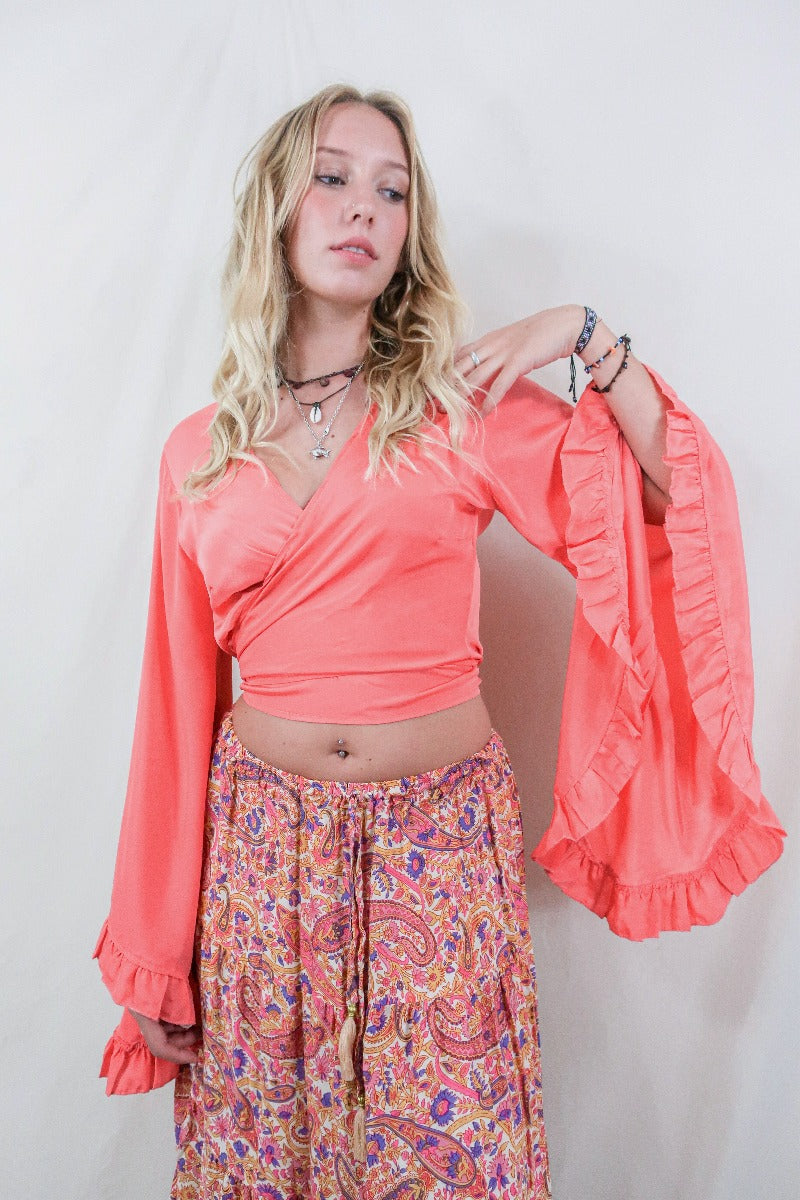 Model wears our Khroma Venus wrap top in a vibrant Miami Peach colour. Inspired by the hippie bohemian 70s with its long butterfly sleeves by All About Audrey