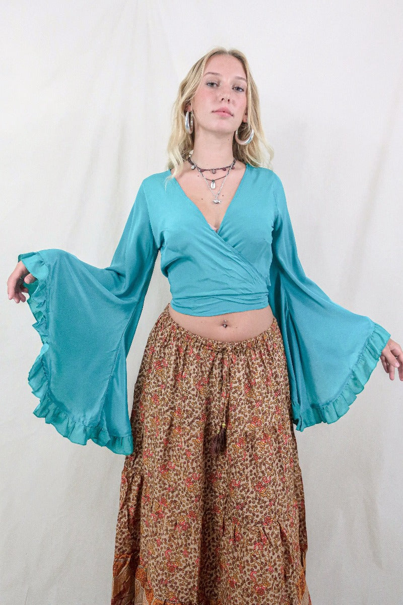 Model wears our Khroma Venus wrap top in a vibrant Ocean Blue colour. Inspired by the hippie bohemian 70s with its long butterfly sleeves by All About Audrey