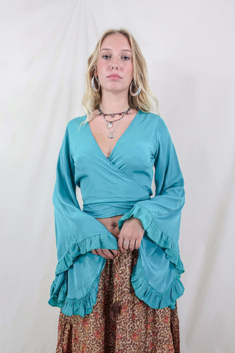Model wears our Khroma Venus wrap top in a vibrant Ocean Blue colour. Inspired by the hippie bohemian 70s with its long butterfly sleeves by All About Audrey