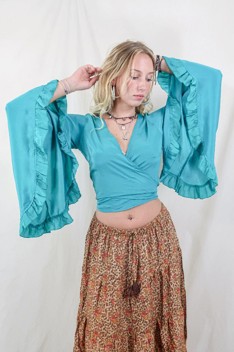 Model wears our Khroma Venus wrap top in a vibrant Ocean Blue colour. Inspired by the hippie bohemian 70s with its long butterfly sleeves by All About Audrey