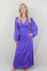 Model wears our retro style Khroma Lola Maxi dress in Electric Lilac. Worn here in a wraparound style, the model shows off the beautiful balloon sleeves and and adjustable waist gives the wearer an elegant shape. By All About Audrey