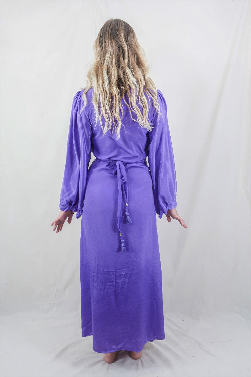 Model wears our retro style Khroma Lola Maxi dress in Electric Lilac. Worn here in a wraparound style, the model shows off the beautiful balloon sleeves and and adjustable waist gives the wearer an elegant shape. By All About Audrey