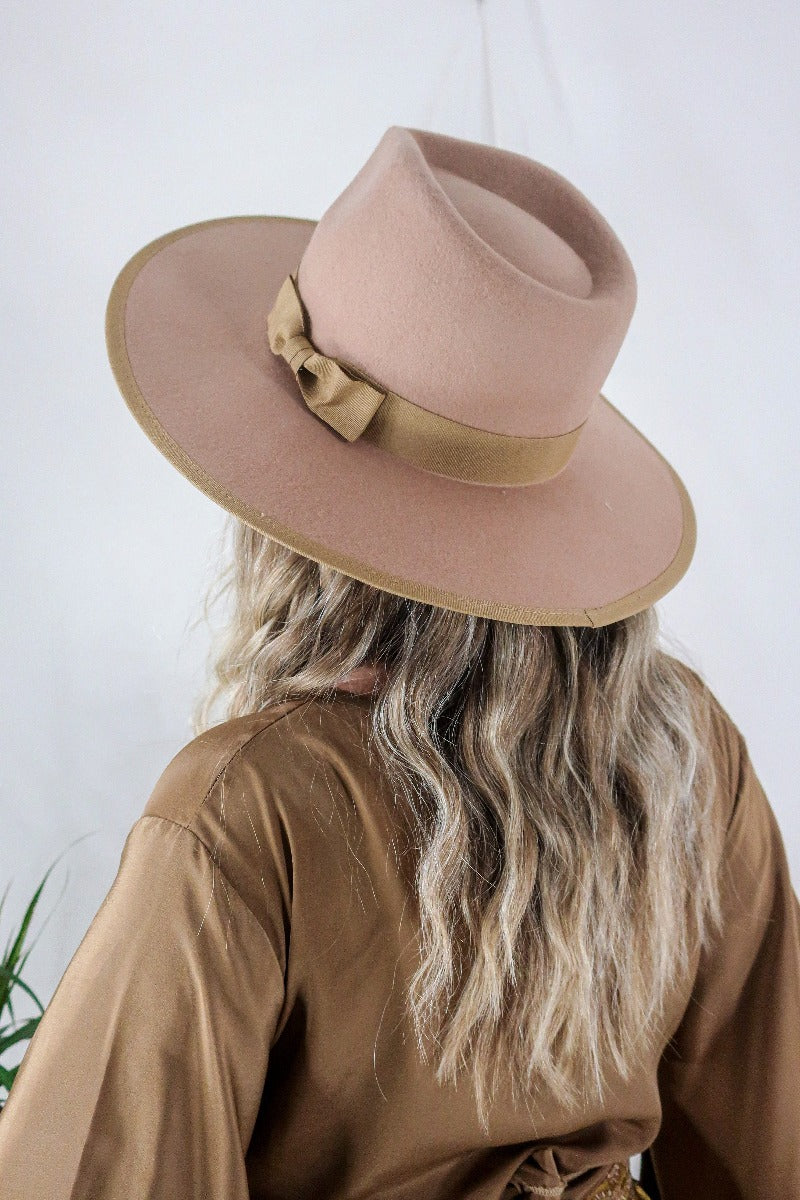 Model wears our Sierra hat in Tan. A natural warm earthy beige inspired by vintage 1970s prairie and western cowboy styles. Classic wide brim and high crown Fedora design with a decorative ribbon and trim by All About Audrey