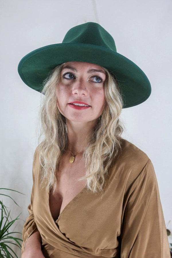 Model wears our Sierra hat in Forest Green. A natural jewelled earthy green inspired by vintage 1970s prairie and western cowboy styles. Classic wide brim and high crown Fedora design with a decorative ribbon and trim by All About Audrey
