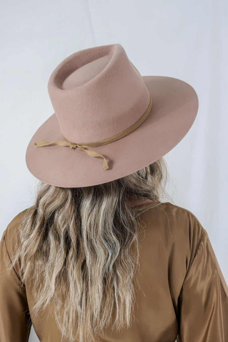 Model wears our Sierra hat in Fawn. A light natural beige inspired by vintage 1970s prairie and western cowboy styles. Classic wide brim and high crown Fedora design with a decorative thin ribbon and simple brim by All About Audrey