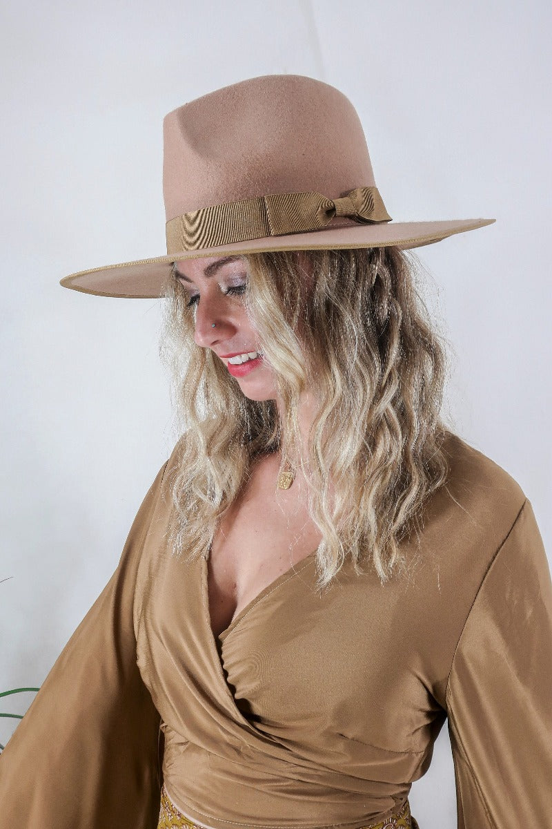 Model wears our Sierra hat in Tan. A natural warm earthy beige inspired by vintage 1970s prairie and western cowboy styles. Classic wide brim and high crown Fedora design with a decorative ribbon and trim by All About Audrey