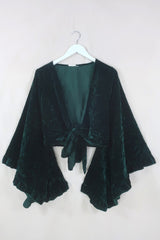 Flatlay of our Khroma Venus Wrap Top in Diesel Green Velvet. 1970's style design with huge butterfly bell sleeves and luxurious retro velvet earthy tones by All About Audrey