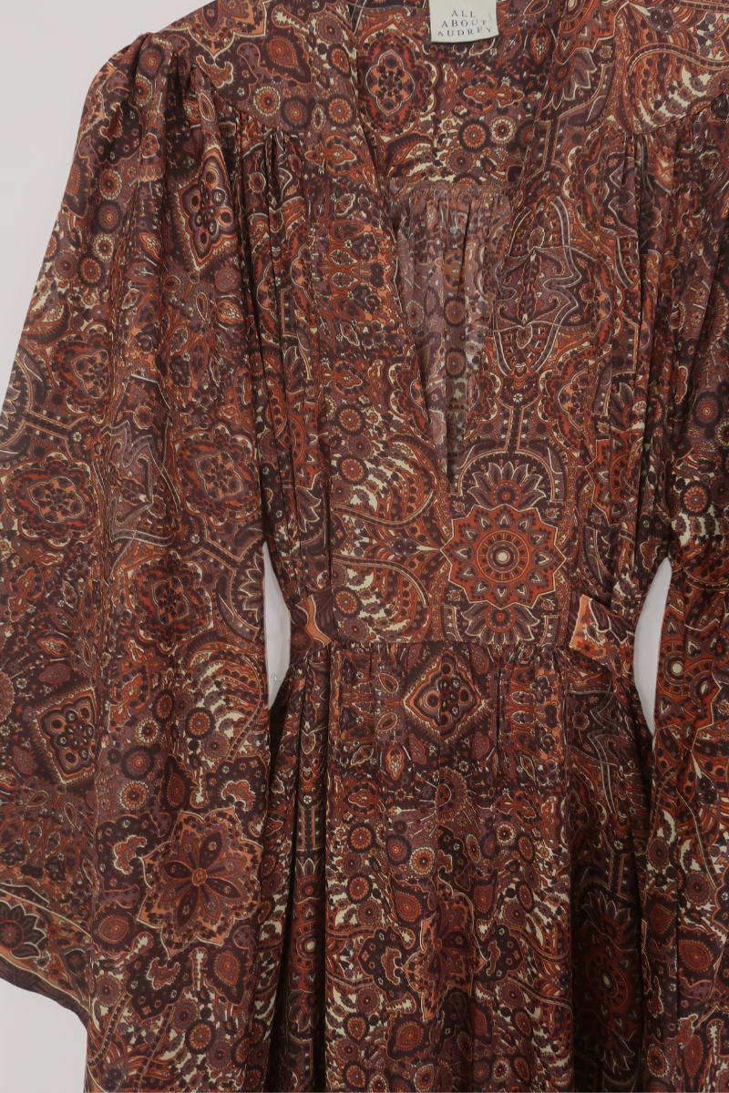 Flat-lay of our Stevie Mandala Kaftan Dress in Dylan Brown. An earthy psychedelic pattern of warm retro brown and orange by All About Audrey