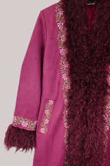Close-up of a burgundy red coat with floral embroidery and maroon fur trim on a light gray background