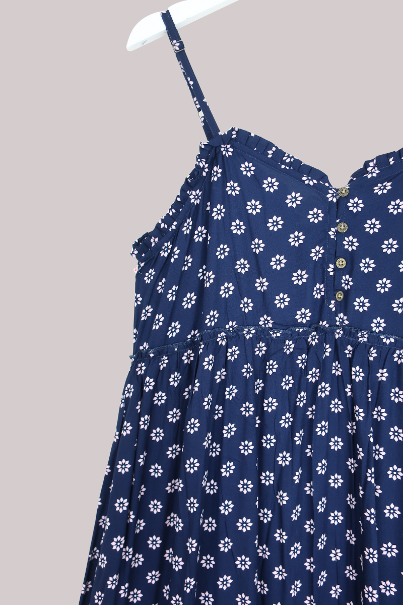 Navy blue dress with white floral pattern on a hanger against a gray background