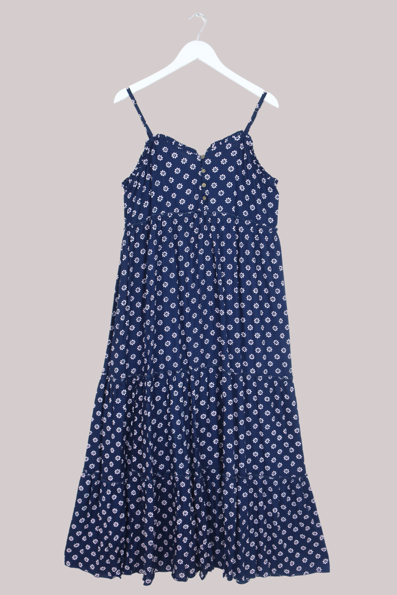 Blue floral dress on a hanger against a beige background