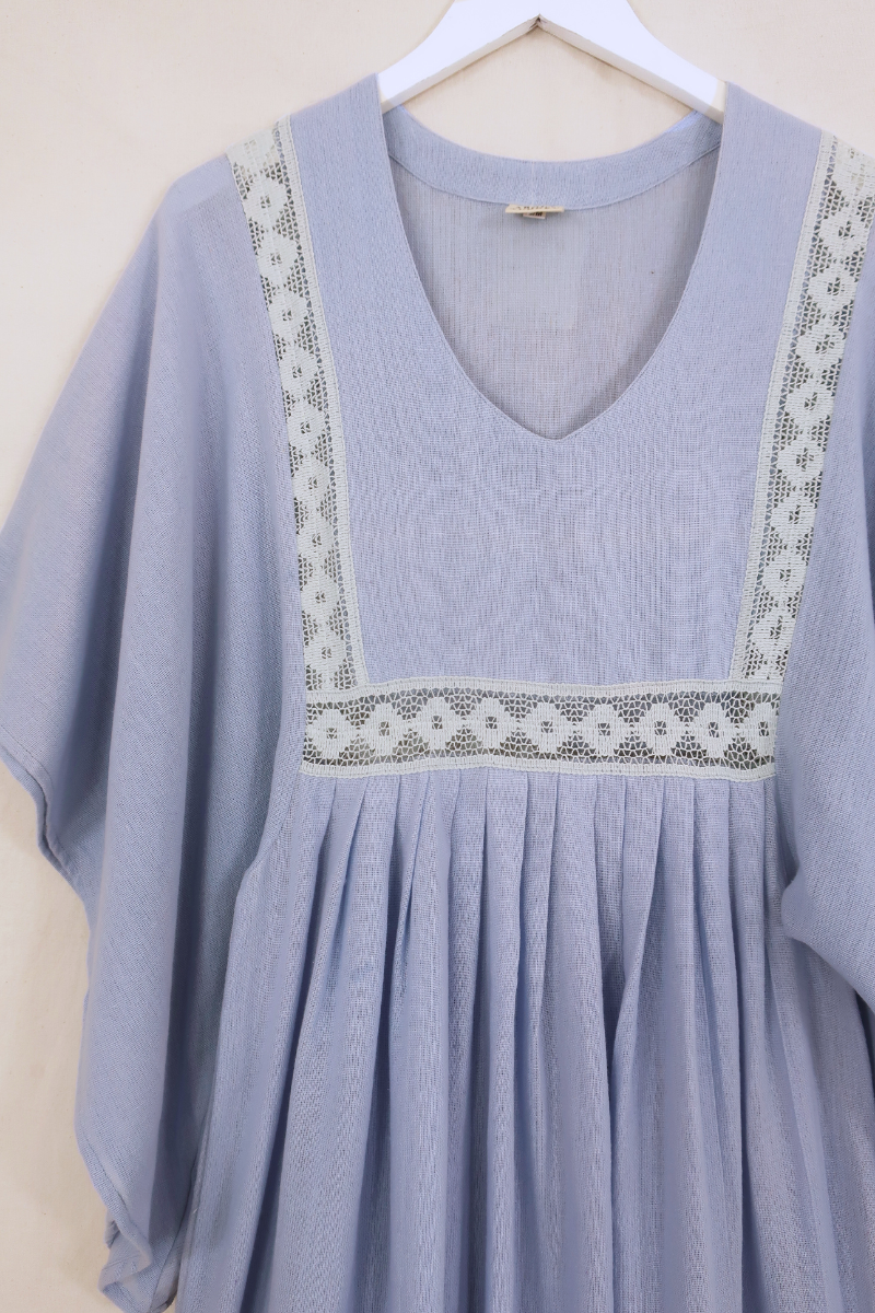 Flat lay of our Cordelia Midi Dress in Cornflower Blue. A folky vintage smock style silhouette with a crochet square bust panel and huge elegant wide sleeves by All About Audrey