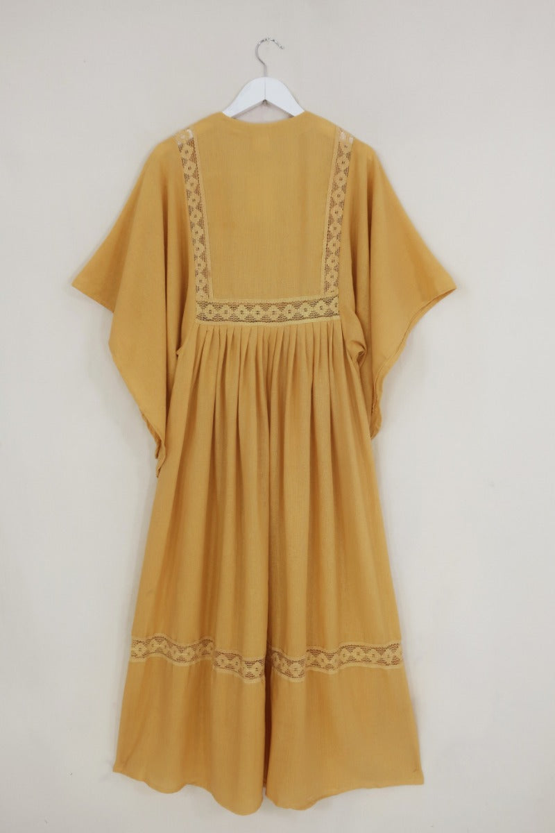 Flat lay of our Cordelia Midi Dress in Daffodil Yellow. A folky vintage smock style silhouette with a crochet square bust panel and huge elegant wide sleeves by All About Audrey