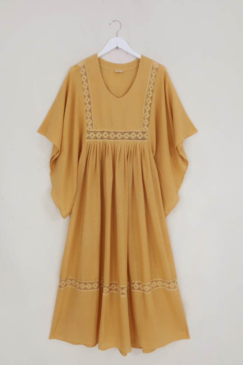 Flat lay of our Cordelia Midi Dress in Daffodil Yellow. A folky vintage smock style silhouette with a crochet square bust panel and huge elegant wide sleeves by All About Audrey