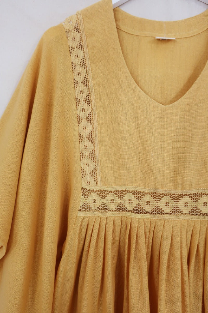 Flat lay of our Cordelia Midi Dress in Daffodil Yellow. A folky vintage smock style silhouette with a crochet square bust panel and huge elegant wide sleeves by All About Audrey