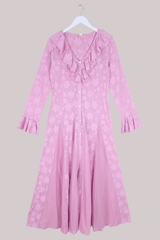 Pink floral dress on a hanger against a neutral background