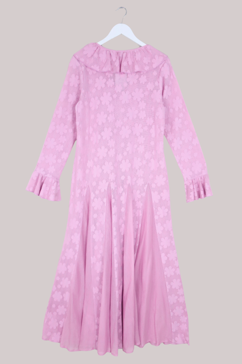Pink dress with long sleeves on a hanger against a gray background