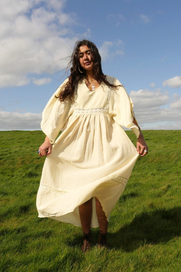 Model wears our Cordelia Midi Dress in Ivory White. Such a folky, 1970s bohemian silhouette with the crochet bust panel and waist plus the huge wide tapered sleeves by All About Audrey 