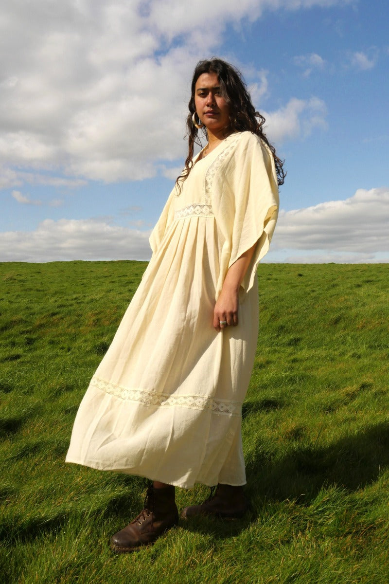 Model wears our Cordelia Midi Dress in Ivory White. Such a folky, 1970s bohemian silhouette with the crochet bust panel and waist plus the huge wide tapered sleeves by All About Audrey
