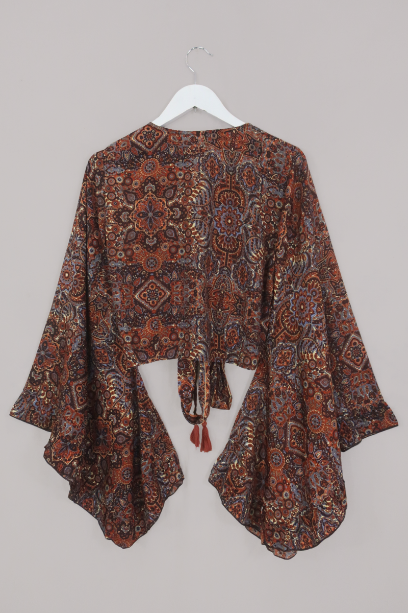 Flat-lay of our Venus Wrap Top in Jagger Lilac & Rust Mandala. A mix of deep umber brown and a contrasting folky blue, all in a kaleidoscope of patterns by All About Audrey