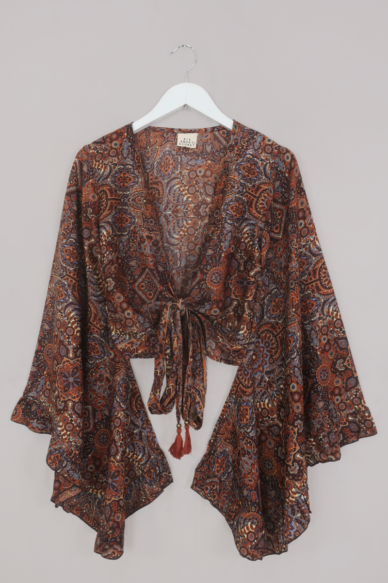 Flat-lay of our Venus Wrap Top in Jagger Lilac & Rust Mandala. A mix of deep umber brown and a contrasting folky blue, all in a kaleidoscope of patterns by All About Audrey