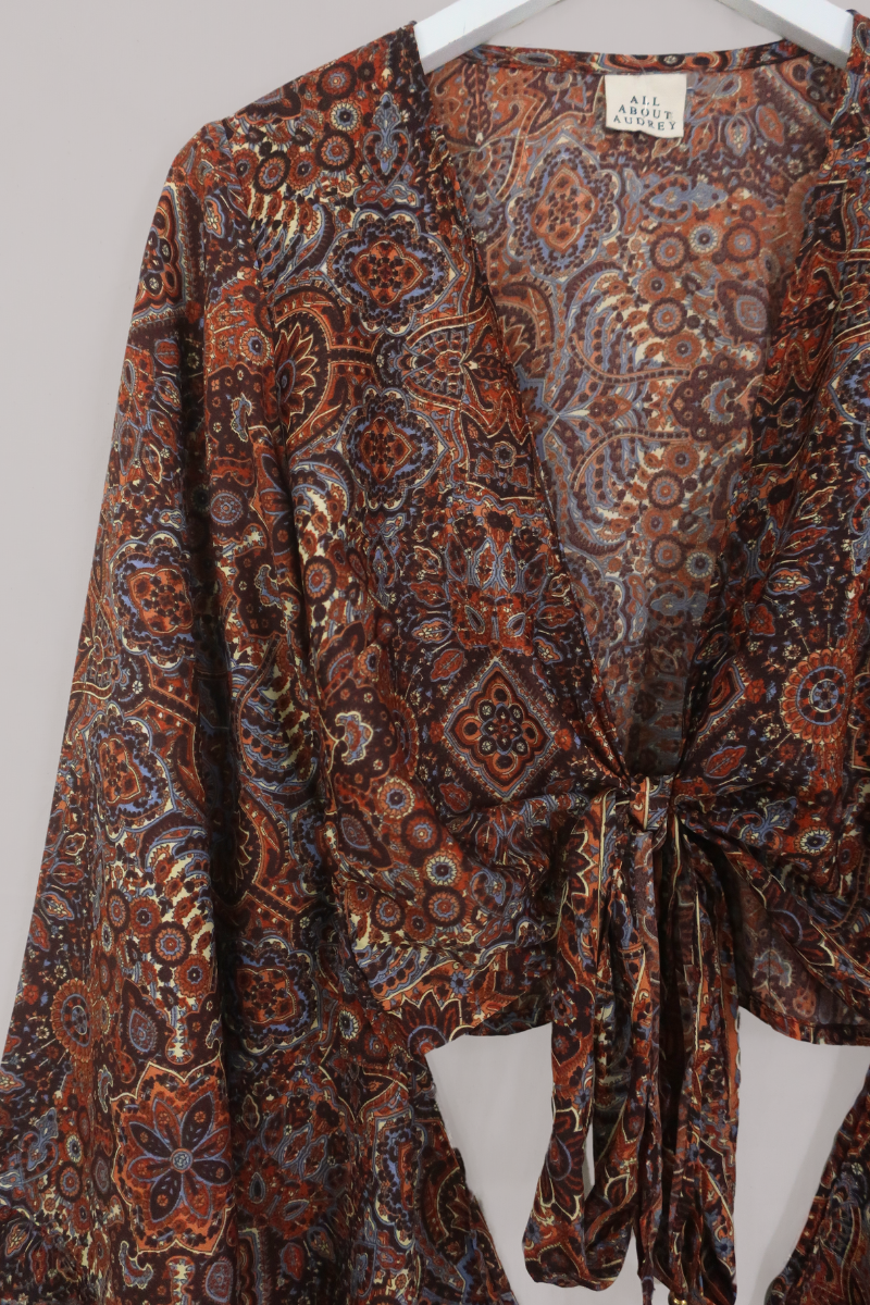 Flat-lay of our Venus Wrap Top in Jagger Lilac & Rust Mandala. A mix of deep umber brown and a contrasting folky blue, all in a kaleidoscope of patterns by All About Audrey