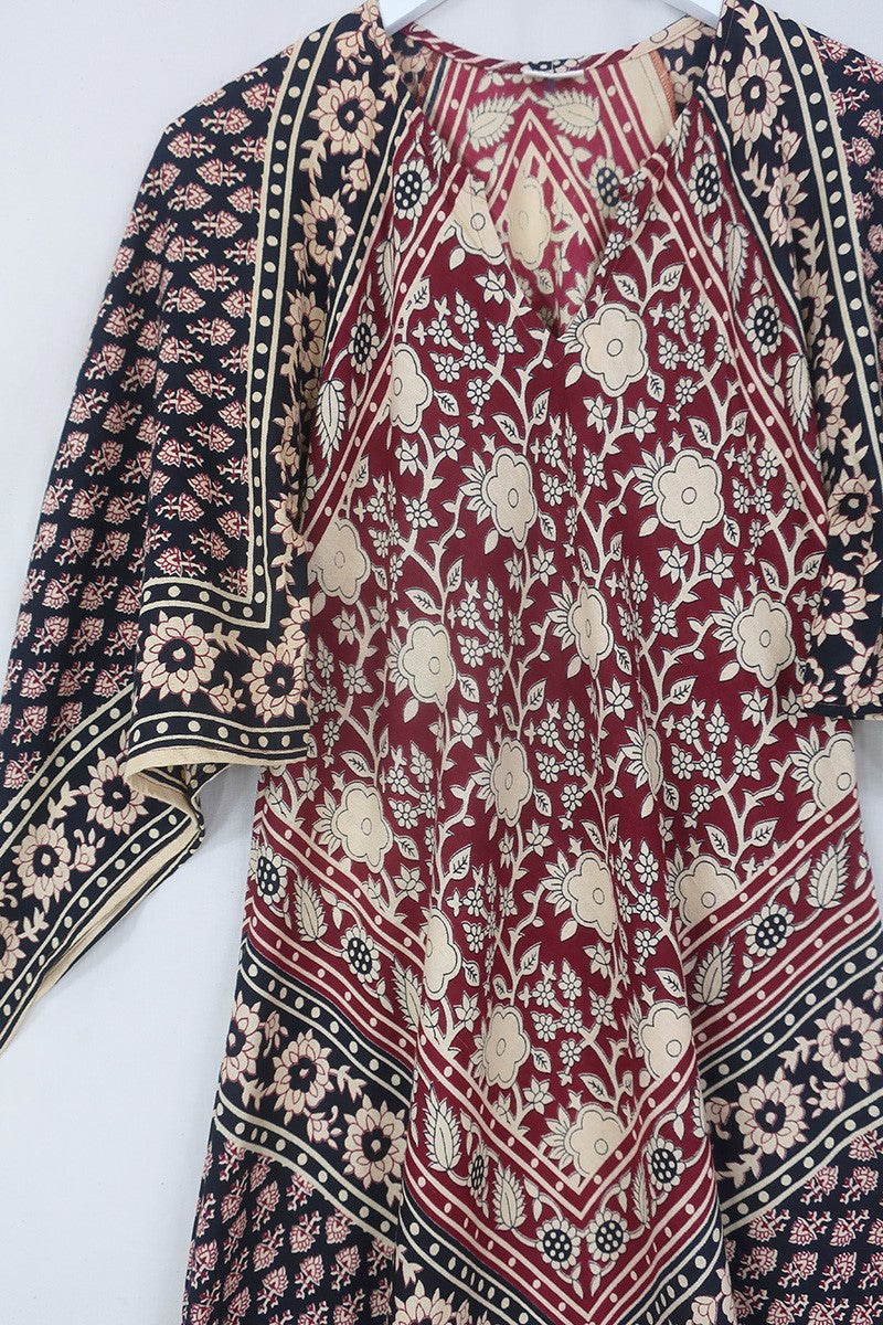 Close up flatlay of our Emmylou Patchwork Maxi Dress in Cherry Red & Black. Showing off the kaftan style with tapered sleeves and maxi length. The print is a beautiful block print patchwork made from Indian cotton by All About Audrey.