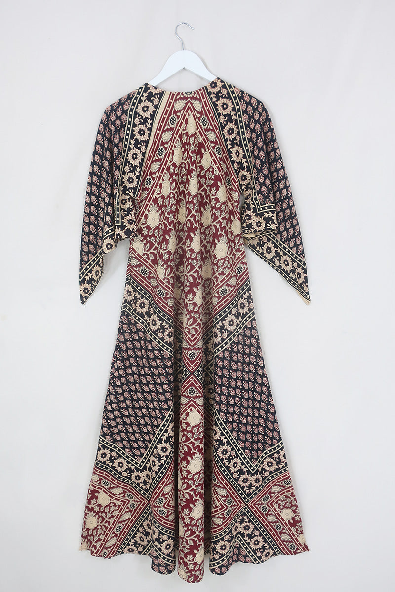 Back flatlay of our Emmylou Patchwork Maxi Dress in Cherry Red & Black. Showing off the kaftan style with tapered sleeves and maxi length. The print is a beautiful block print patchwork made from Indian cotton by All About Audrey.
