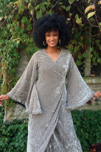 Model wears our Khroma Venus Maxi Dress as a wrap style, tied at the back and showing off the huge retro floaty bell sleeves. A beautiful Stardust Grey Velvet by All About Audrey