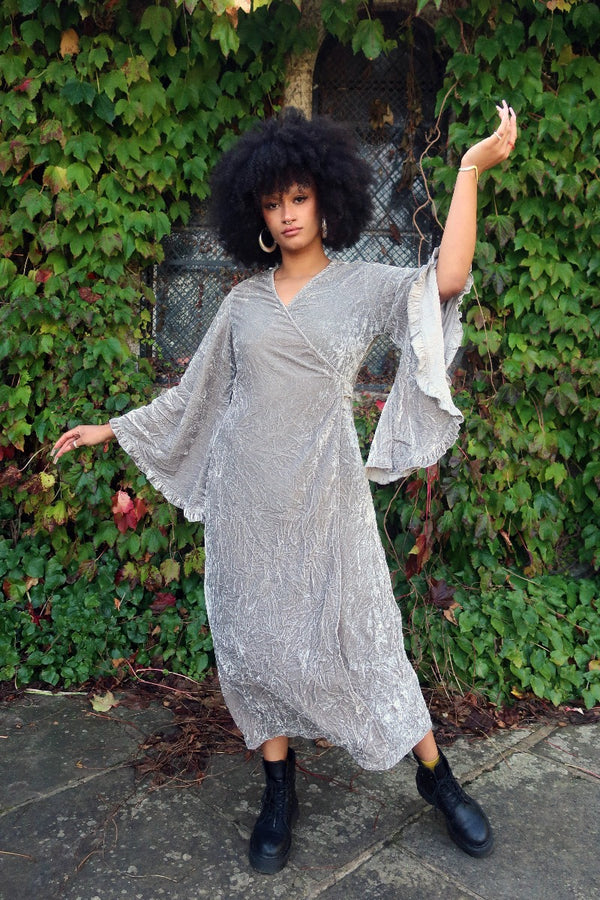 Model wears our Khroma Venus Maxi Dress as a wrap style, tied at the back and showing off the huge retro floaty bell sleeves. A beautiful Stardust Grey Velvet by All About Audrey