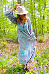 close up photograph of model wearing florence maxi dress in powder blue and peach pink paisley floral design with high neck and button-down smocked top with balloon sleeve handmade in sustainable rayon from all about audrey