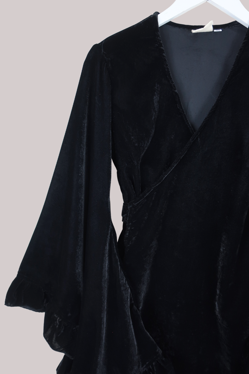Black velvet coat on a hanger against a light background