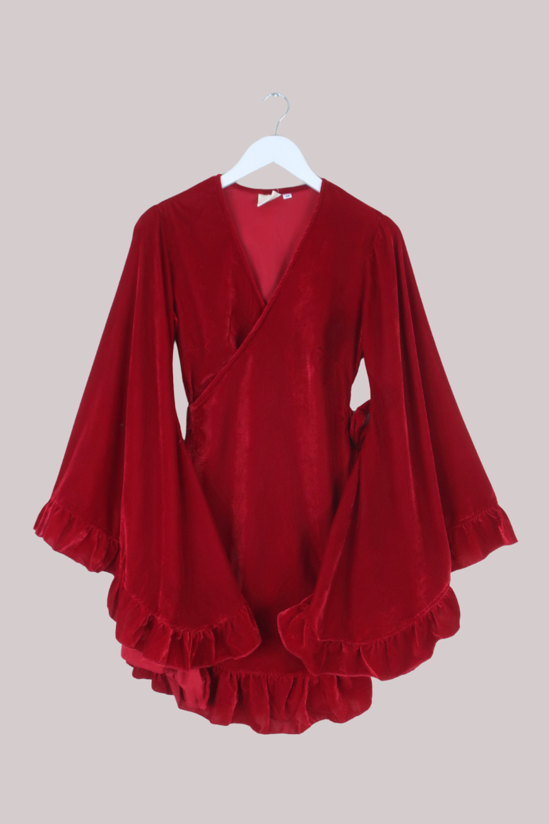 Red velvet dress with ruffled details on a beige background