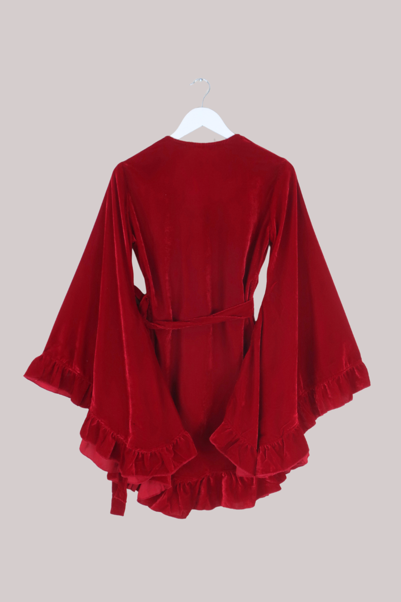 Red velvet dress with ruffled details on a beige background