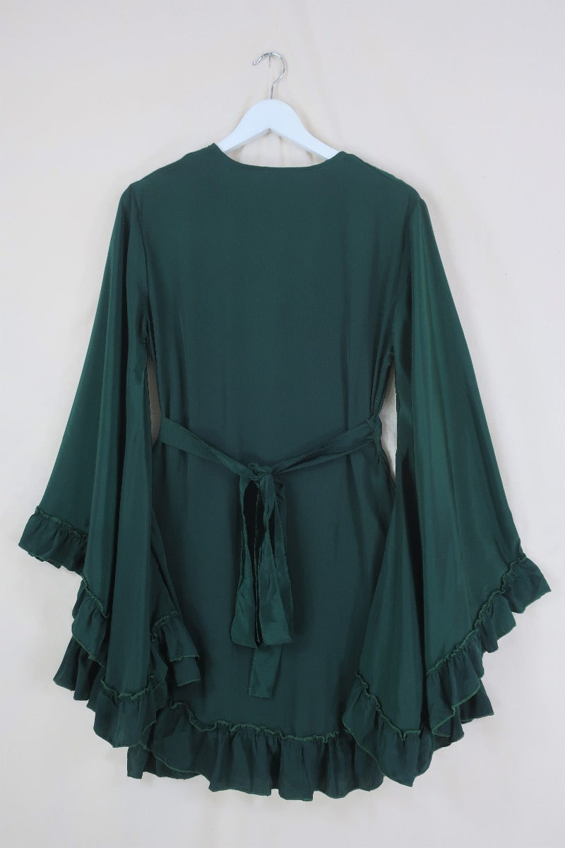 Flat lay of our Venus Khroma wrap dress in Archer Green, a darker jewel green tone which is easy to style and versatile to wear! Inspired by 70's bohemia by All About Audrey