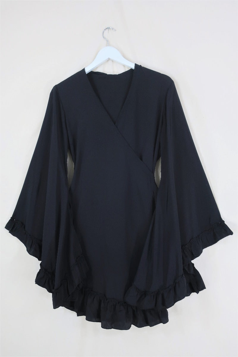 Flat lay of our Venus Khroma wrap dress in Vampy Black, a sleek and sultry classic which is easy to style and versatile to wear! Inspired by 70's bohemia by All About Audrey