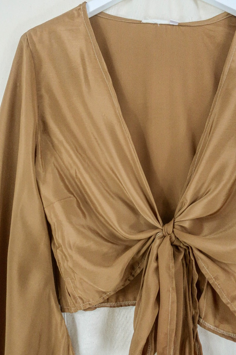 Flat lay off our Venus Khroma wrap top in Golden Sands, a neutral, earthy, antique gold tone which is easy to style and versatile to wear! Inspired by 70's bohemia by All About Audrey